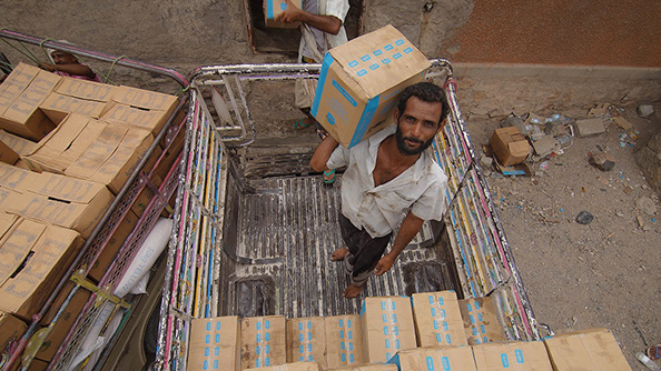 Workers stack food assistance in a warehouse in Lahj on 1 July 2019. Photo credit: WFP/Saleh Baholis