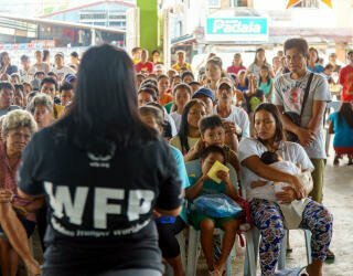 WFP-ansatte forklarer registreringsprosessen til mennesker i Irosin-samfunnet som deltar i et værbasert klimafinansieringsprosjekt. Foto: WFP Philippines/Arete