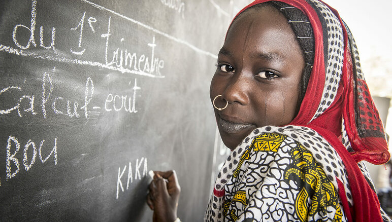Kaka Marabou skriver navnet sitt på en tavle på skolen hennes i Yakoua ved Tsjadsjøen. Flyktninger, fordrevne og andre fattige lokalsamfunn i området rundt Tsjadsjøen er avhengige av humanitær bistand for å overleve, og tilgangen til utdanning er også begrenset. WFP/Giulio d'Adamo